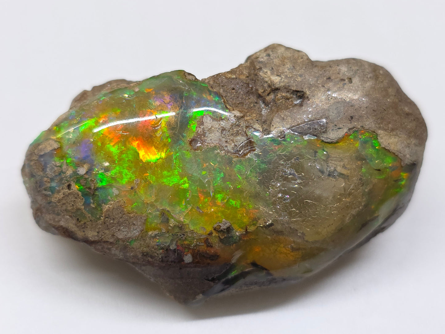 Opal stone with colorful play of light on a white background